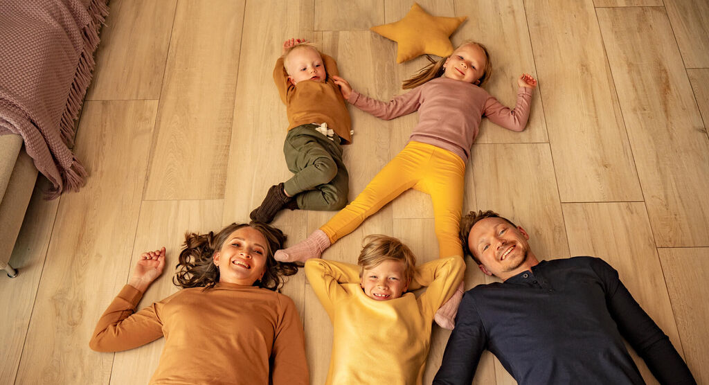 A happy family lying on the floor enjoying their time together, surrounded by a star-shaped pillow