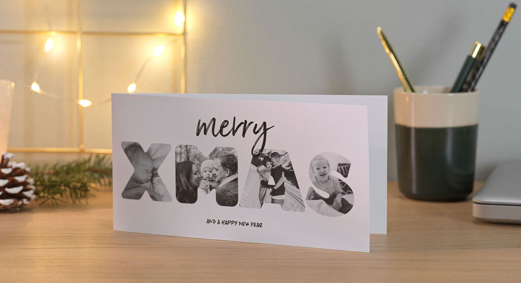 An elegant folded Christmas card with the text 'merry XMAS' in big letters. Photos of happy people are inserted in the letters.