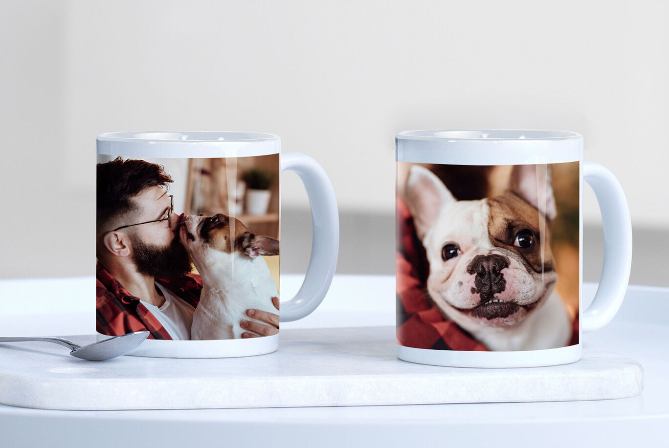 Two mugs, one with a dog picture and the other with a friendly bulldog, on a table.