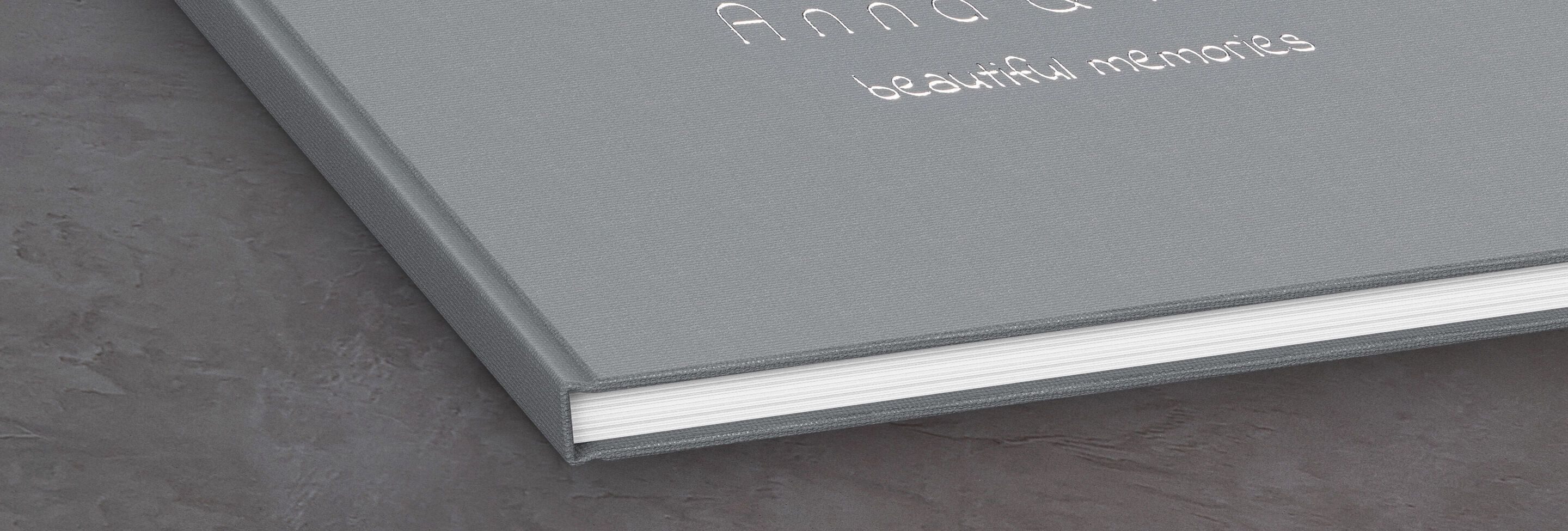 Gray CEWE photo book titled 'Anna &' and subtitle 'beautiful memories' on a table.