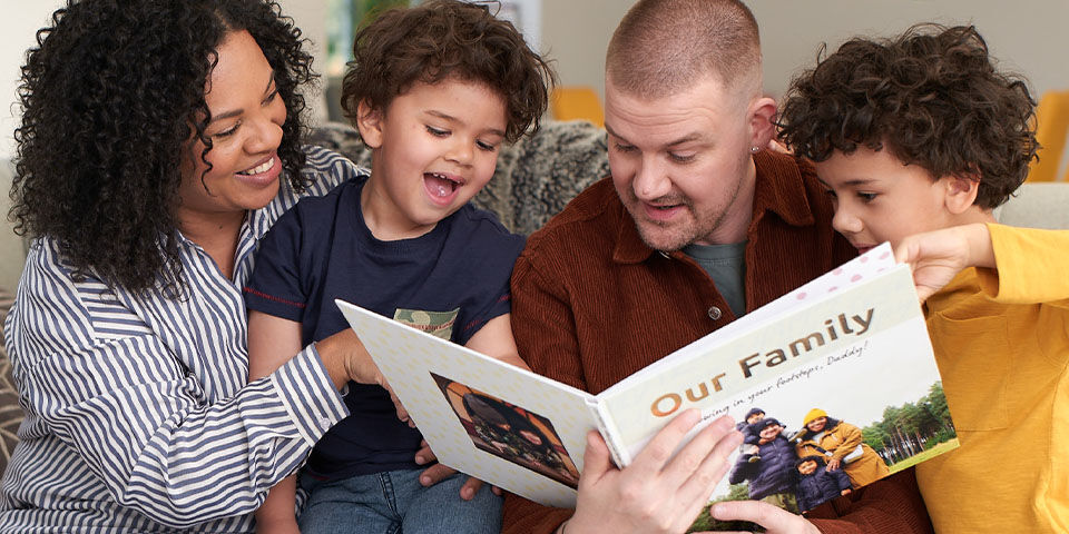 Family sitting together on the couch, looking at a photo book.